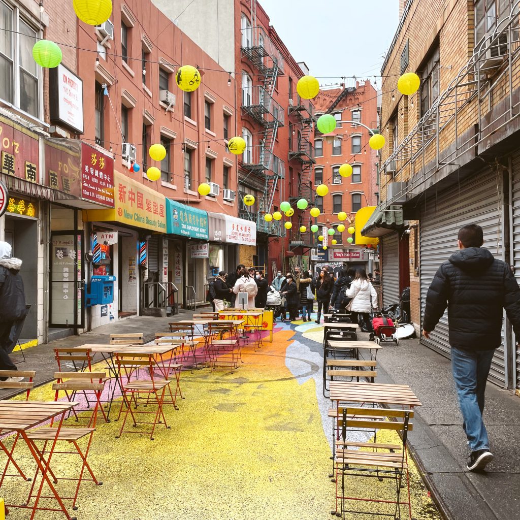 A view of Doyers street withers brightly painted street and cafe tables.