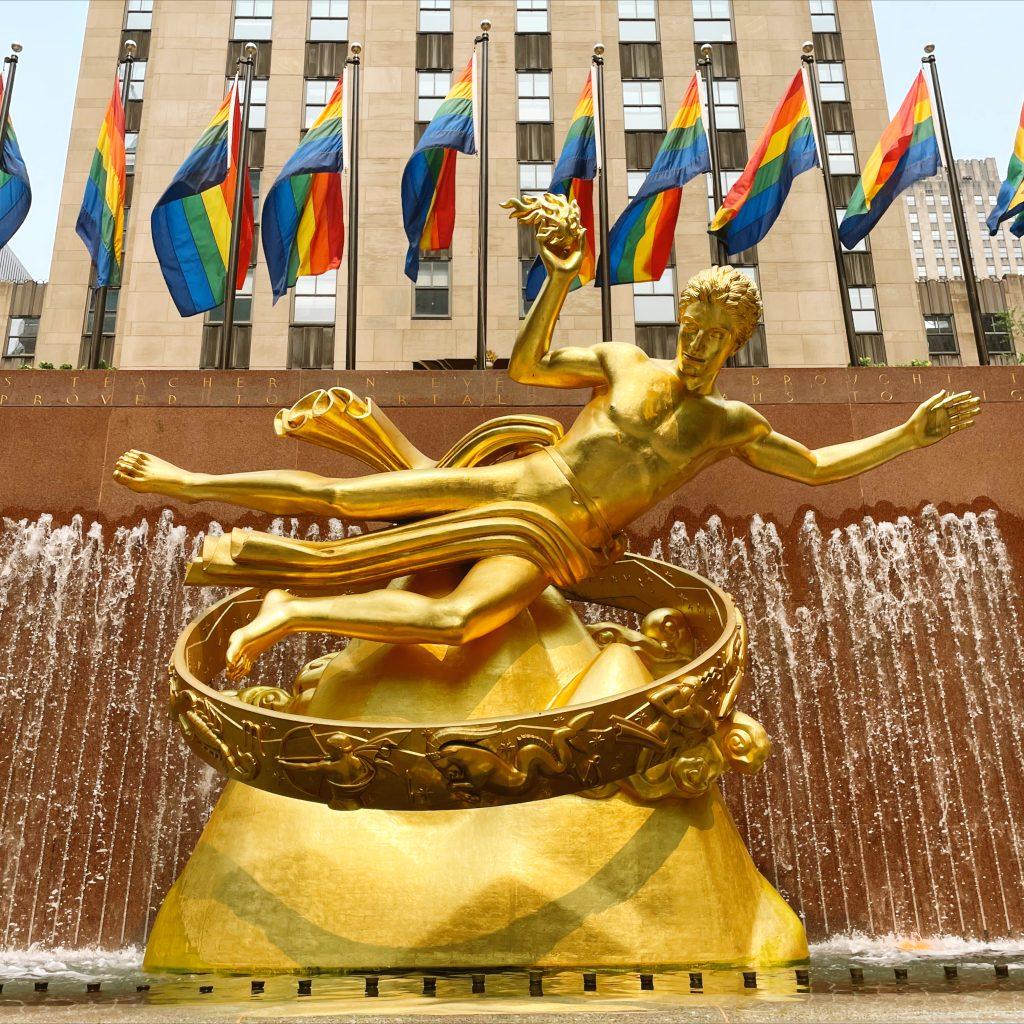 Rockefeller Center Statue against the cascading waterfall and flags.