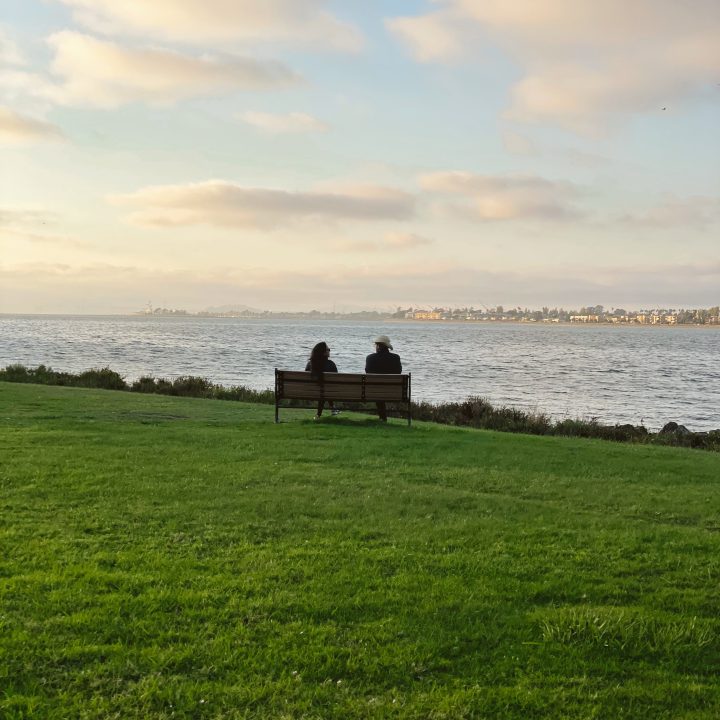 Couple sitting on a bench overlooking the city along the Bay Farm Island trail.