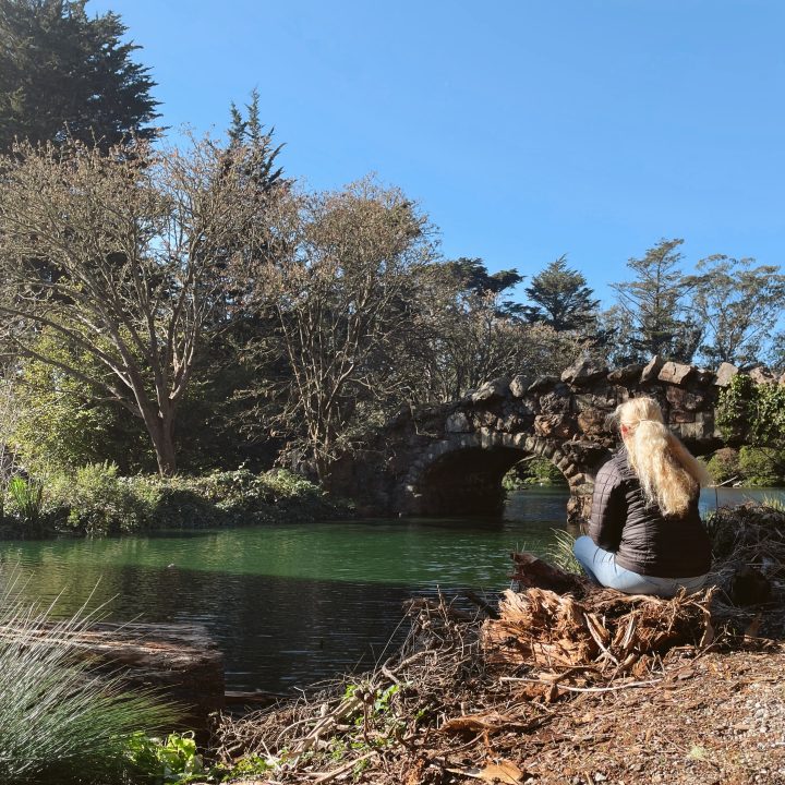 Carrie sitting by a stone bridge in safe Golden Gate Park