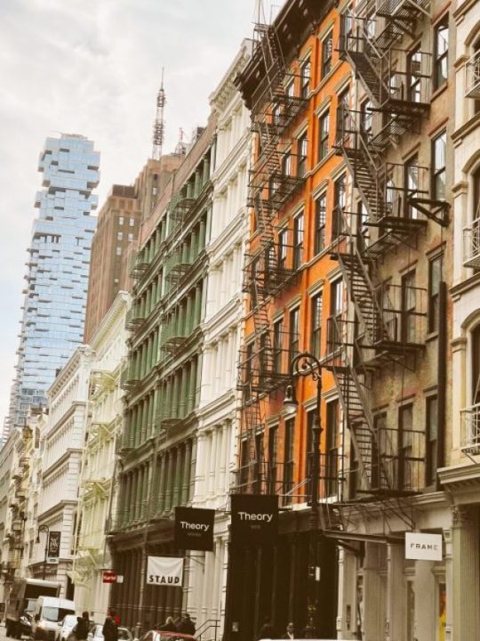 Jenga Building in Tribeca, a unique skyscraper with protruding floors, set against a backdrop of colorful buildings.