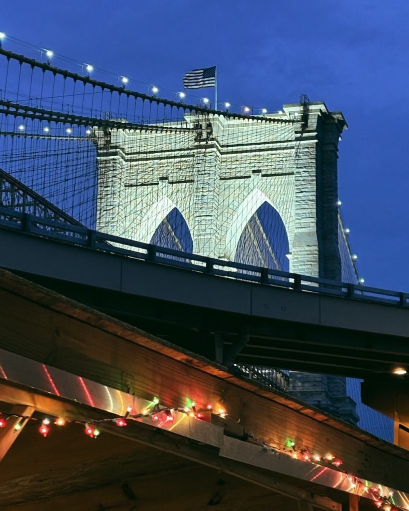 A nighttime view of the Brooklyn Bridge from South Street Seaport