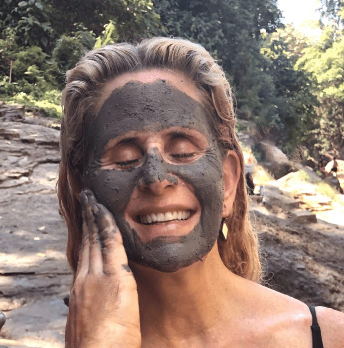 Woman smiling with eyes closed and mud on her face