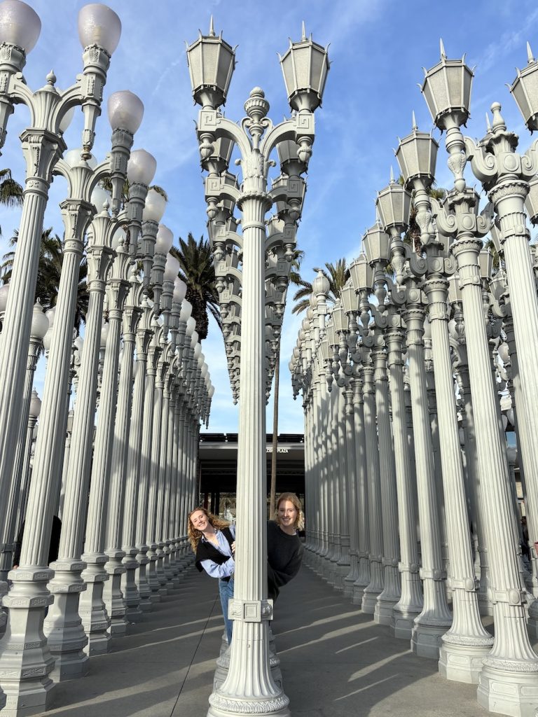 Carrie Green-Zinn's daughters peeking out behind the lampposts of the Los Angeles County Museum of Art (LACMA)