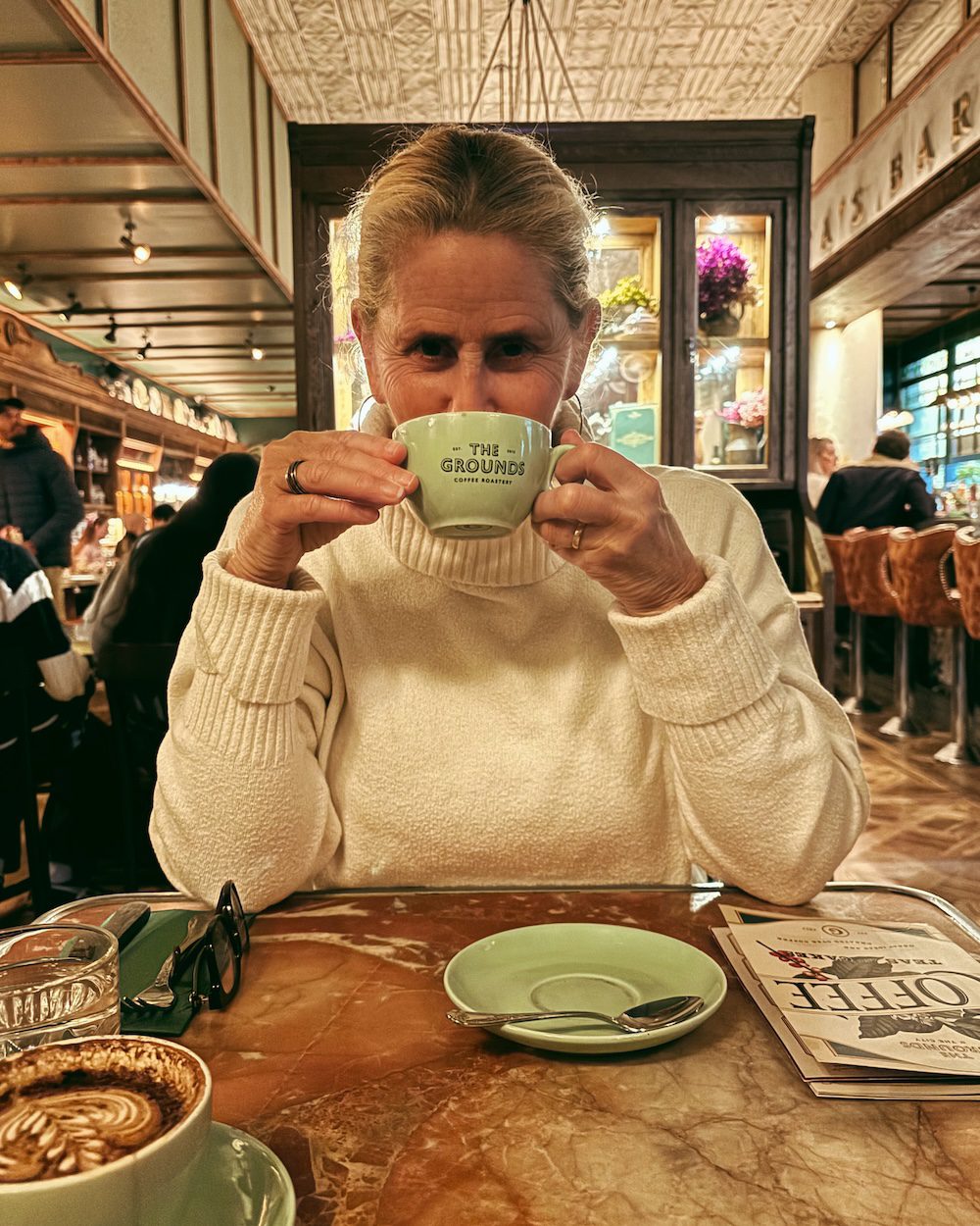 Carrie Green-Zinn sipping coffee at The Grounds restaurant in Sydney, Australia