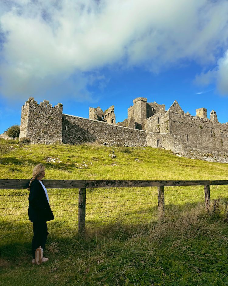 Carrie Green Zinn wearing an Athleta rain jacket while looking at a castle in Ireland